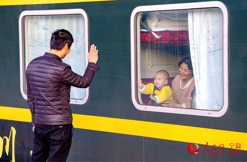 1月28日，銀川至杭州的K1805次列車即將始發，一位年輕的打工者隔著車窗送妻子與兒子回家過年