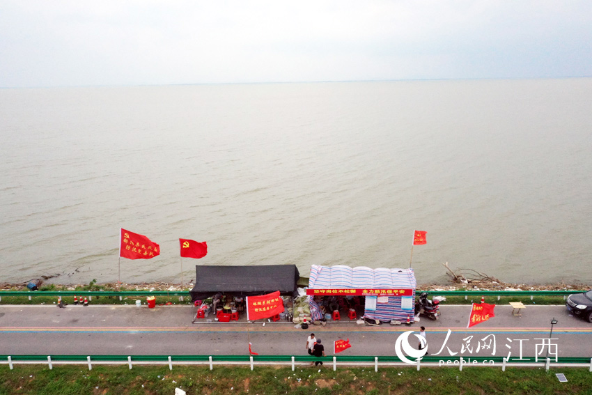 19日，鄱阳湖水惊涛拍岸，珠湖联圩的大堤上党旗迎风飘扬。（人民网 时雨/摄）