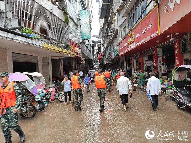 武警官兵携带铁锹在营山县双流镇油坊街到双流小学路段开展清淤工作。