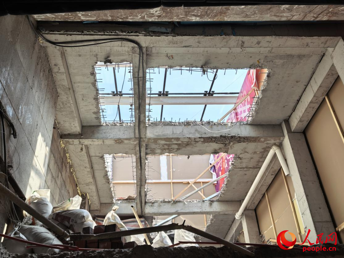新华时尚购物广场11号门出入口二层违建处堆放了各种废弃建筑材料。 人民网记者李洋摄
