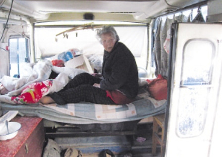 老人见记者来访，从车内的床上探起身来。